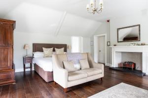 ein Schlafzimmer mit einem Bett, einem Stuhl und einem Kamin in der Unterkunft Millbrook Lodge in Ballynahinch