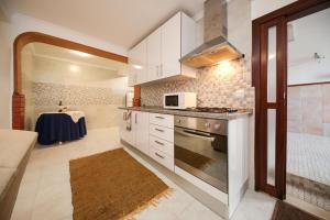 une cuisine avec des armoires blanches et un four à plaques de cuisson dans l'établissement ManelMar O Refúgio, à Nazaré