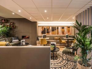 a lobby with tables and chairs and plants at Mercure Oostende in Ostend