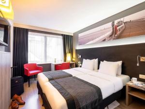 ein Hotelzimmer mit einem großen Bett und einem roten Stuhl in der Unterkunft Mercure Oostende in Ostende