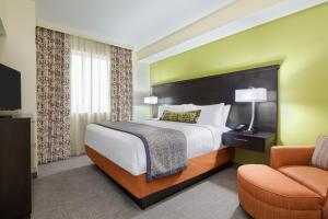 a hotel room with a bed and a chair at Staybridge Suites - Miami International Airport by IHG in Miami