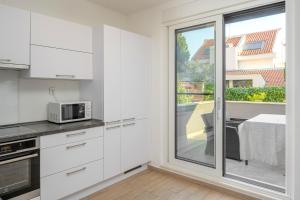 a kitchen with white cabinets and a large window at LUX Holiday Apartment on KASUNI Beach in Split in Split