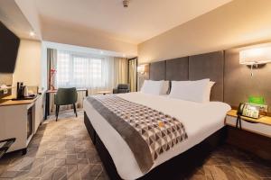 a hotel room with a large bed and a desk at Holiday Inn Bucharest - Times by IHG in Bucharest
