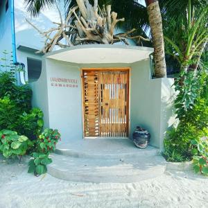 a small house with a wooden door on a beach at Hudhuveli Kamadhoo in Milaidhoo