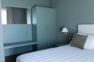 Hotel Enzo في بورتو ريكاناتي: غرفة نوم بسرير ابيض وجدار ازرق
