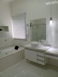 La salle de bains blanche est pourvue d'une baignoire, d'un lavabo et d'une baignoire. dans l'établissement Pousada São Francisco, à São João Batista do Glória