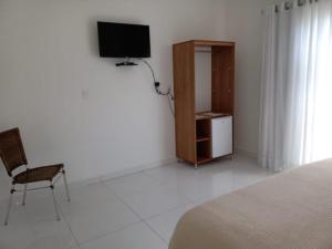 a bedroom with a bed and a television and a chair at Pousada São Francisco in São João Batista do Glória