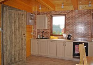 a kitchen with white cabinets and a brick wall at Domki Górskie Zacisze in Koniaków