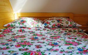 a bed with two pillows and a floral comforter at Domki Górskie Zacisze in Koniaków