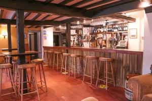 un bar con fila di sgabelli da bar di The Hawk & Buckle Inn a Llannefydd
