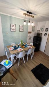 a dining room table with white chairs and a kitchen at Zala Holiday Apartman in Keszthely