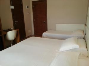 two beds in a hotel room with white sheets at AmbientHotels Panoramic in Rimini