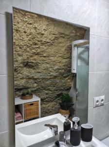 baño con lavabo y pared de piedra en Casa cueva La Tosca en Setenil