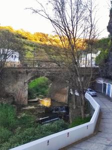 un ponte sopra un fiume con una macchina parcheggiata sotto di Casa cueva La Tosca a Setenil