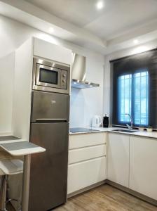 eine Küche mit einem Kühlschrank aus Edelstahl und weißen Schränken in der Unterkunft Casa cueva La Tosca in Setenil de las Bodegas