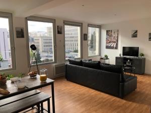 a living room with a black couch and large windows at HYPER CENTRE - WIFI FIBRE GRATUIT - JERGWELOH - Le New Yorkais in Caen