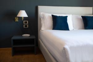 un letto bianco con cuscini blu accanto a un comodino di Hotel Enzo a Porto Recanati