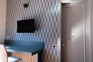 a room with a blue desk and a tv on a wall at Hotel Enzo in Porto Recanati