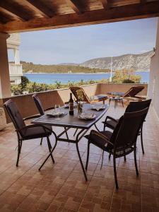 una mesa y sillas en un patio con vistas al océano en Apartments Rina - Kneže, en Račišće