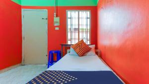 Habitación pequeña con cama en una pared roja en Zaina Tourist Home, en Kollam