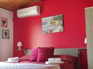 ラグーザにあるNulla 1の赤い壁のベッドルーム1室、ピンクの枕付きのベッド1台が備わります。