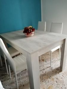una mesa blanca con un tazón de flores. en Appartamento vacanze Piazza del Popolo en Marsala