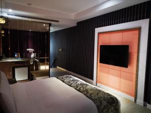 a bedroom with a bed and a television on a wall at Love Story Motel in Taipei