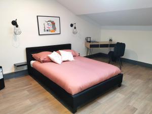 sypialnia z łóżkiem z różową pościelą i biurkiem w obiekcie Logement - Nuit tendance centre ville de Mâcon E w mieście Mâcon