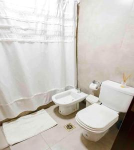 a white bathroom with a toilet and a sink at Genetrix 10 - Bon Repos in San Miguel de Tucumán