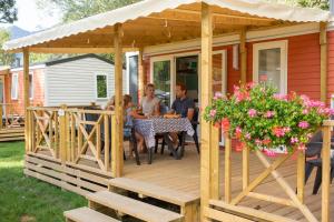 un grupo de personas sentadas en una mesa en una terraza de madera en Camping RCN Belledonne, en Le Bourg-dʼOisans