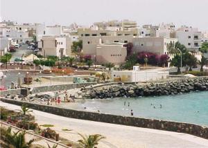 a beach with people in the water and buildings at Laurainu in Puerto del Rosario