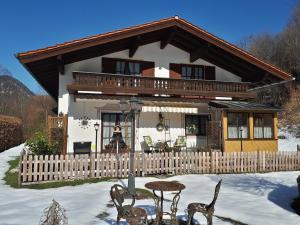 une maison avec une clôture en bois dans la neige dans l'établissement Ferienwohnung Rutz, à Ruhpolding