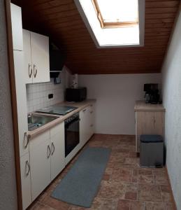 d'une cuisine avec des placards blancs et une lucarne. dans l'établissement Ferienwohnung Rutz, à Ruhpolding
