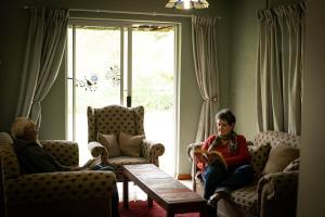 dos mujeres sentadas en una sala de estar leyendo libros en Manna Self Catering Guesthouse, en Graskop