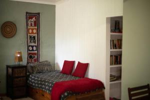 Manna Self Catering Guesthouse في غراسكوب: غرفة نوم عليها سرير ومخدات حمراء
