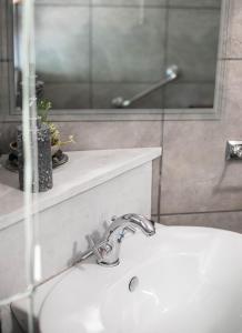 ein Badezimmer mit einem weißen Waschbecken und einem Spiegel in der Unterkunft Manna Self Catering Guesthouse in Graskop