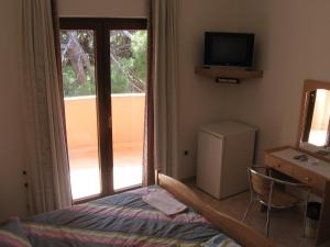 Schlafzimmer mit einem Bett, einem TV und einem Fenster in der Unterkunft Guest House Caterina in Poreč