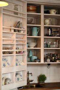 a kitchen cabinet filled with dishes and a sink at B19 Kuldiga in Kuldīga