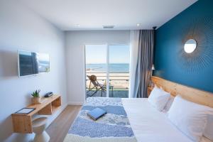 a bedroom with a bed and a view of the ocean at Hôtel Café Miramar in Le Grau-du-Roi