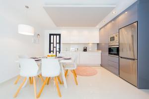 cocina con armarios blancos, mesa y sillas en Luxurious 2 Bedroom Apartment near the beach, en Torre de la Horadada