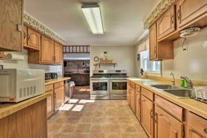 a large kitchen with wooden cabinets and stainless steel appliances at Serene Saxton Lodge 7 Mi to Lake Raystown! in Barnettstown
