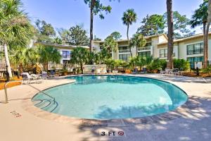 una gran piscina con sillas y palmeras en Hilton Head Island Condo 5 Min Walk To Beach!, en Hilton Head Island