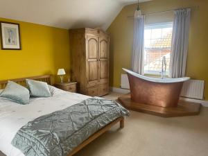 a bedroom with a bed and a tub in a window at Common Farmhouse in Newark-on-Trent