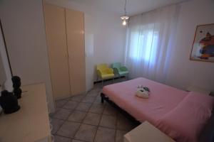 1 Schlafzimmer mit einem rosa Bett und 2 Stühlen in der Unterkunft Lignano Pineta nice flat in Lignano Sabbiadoro