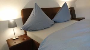 a bed with two blue pillows on it with a night stand at An der grünen Donau - Ferienwohnung, wir bieten keine Parkplätze, Verpflegung oder Tücher an, Parken gegenüber auf der Straßenseite möglich in Immendingen