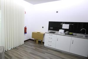 a kitchen with white counters and a sink and radiator at O Casario in Mirandela