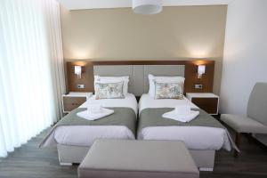 um quarto de hotel com duas camas e uma cadeira em O Casario em Mirandela