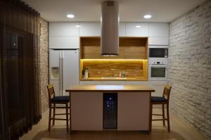 a kitchen with a counter with chairs and a refrigerator at Ravila Puhkemaja in Kuressaare