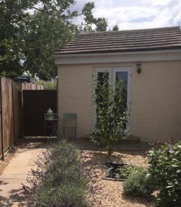 a small house with a fence and a table at The Annexe at Asbit Lodge in Mildenhall