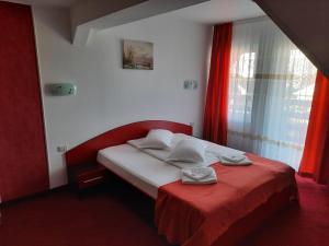1 dormitorio con 1 cama con manta roja y ventana en Pensiunea D&D, en Făgăraş